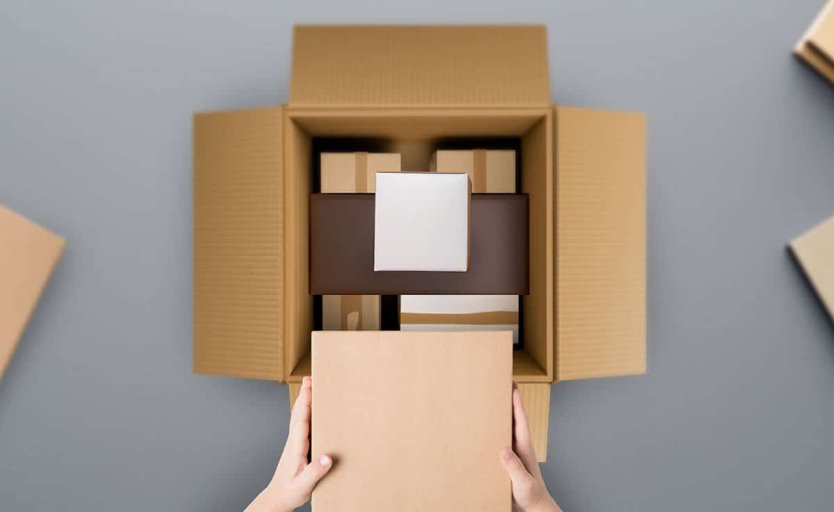 box with assorted smaller boxes inside it. A worker holding a another box that needs to be added in.